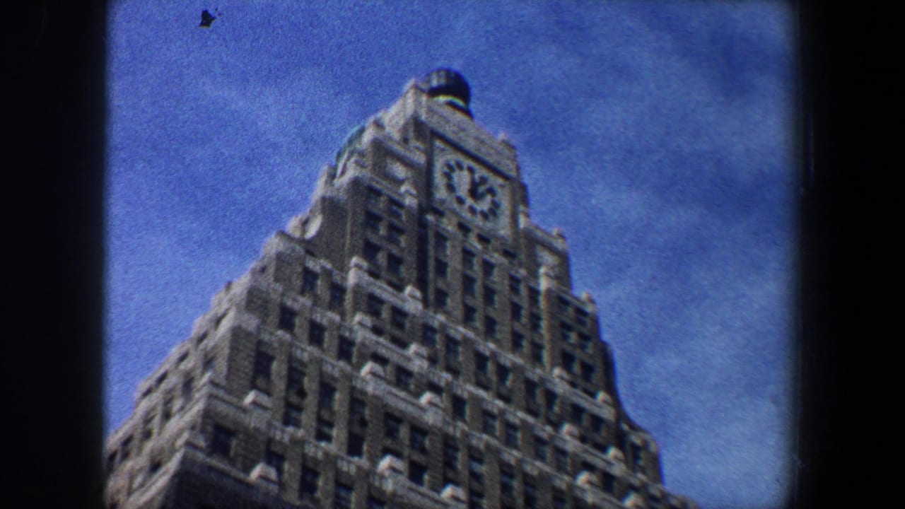 Clock-topped skyscraper viewed from below against blue sky.