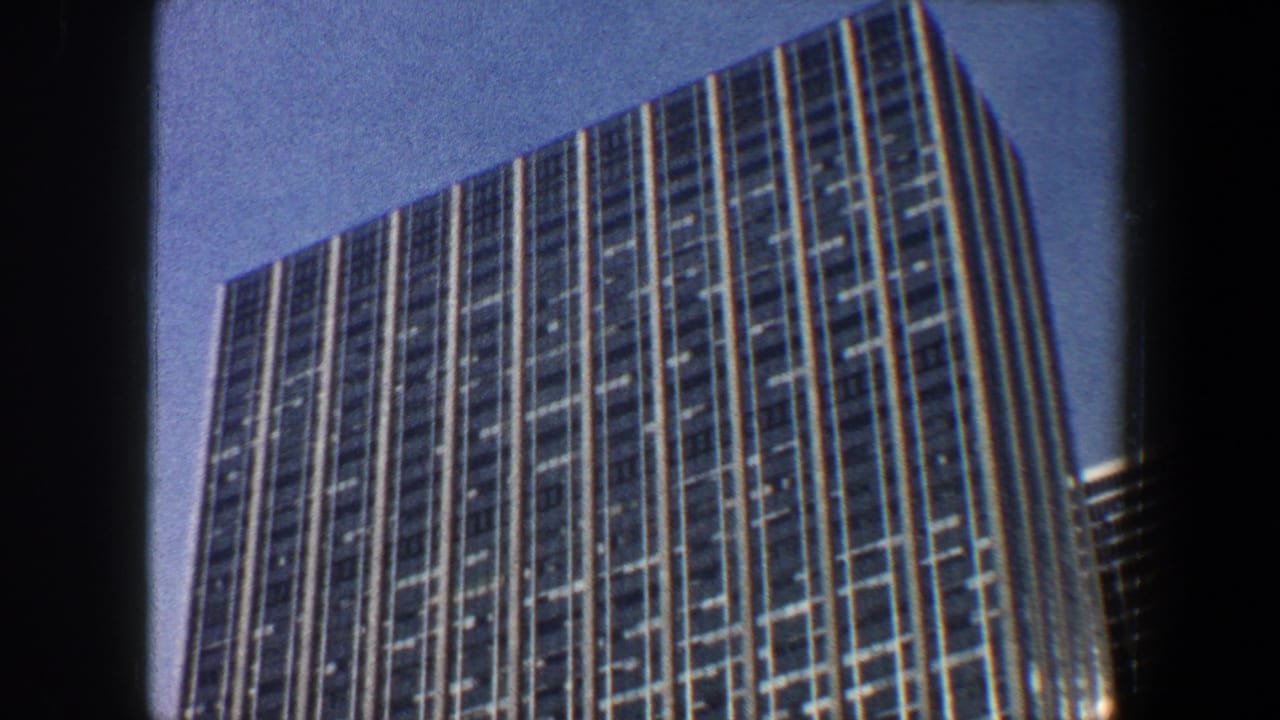 Tall gridded skyscraper facade seen from below with dark frame borders.