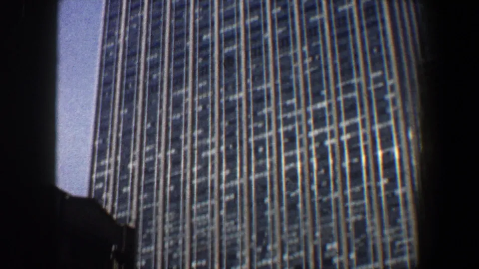 1960 New York City frame showing a close upward angle on a glass-and-grid high-rise facade.