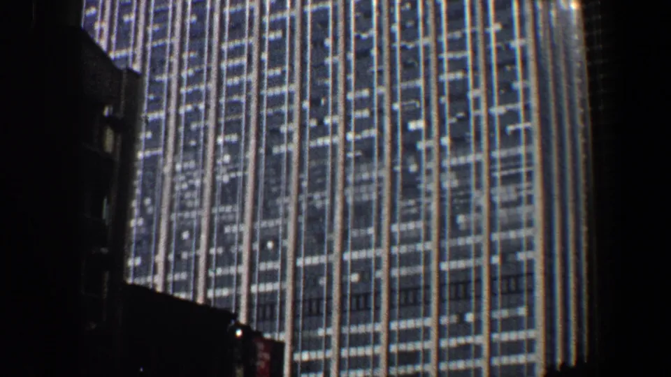 1960 New York City home-movie frame showing the lower facade of a tall building from a street-level angle.