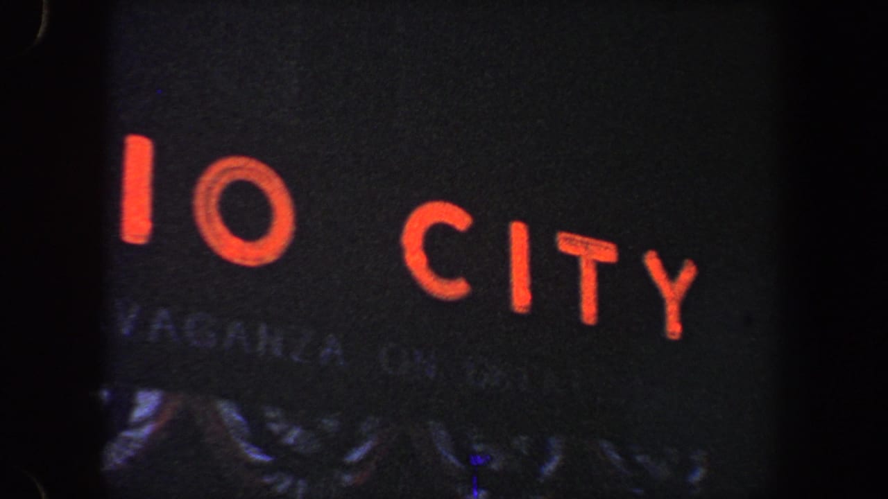 Red illuminated letters on a dark city sign with film edge visible.