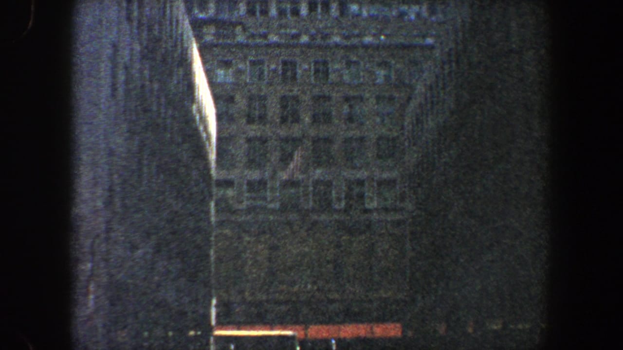 Dark low-angle view of tall city buildings with a hazy facade and film-edge shadow.