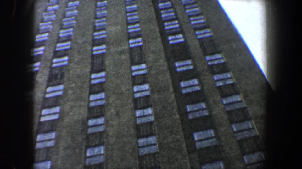 Close upward-looking frame of a dark skyscraper in New York City, with windows stretching through the 8mm frame.