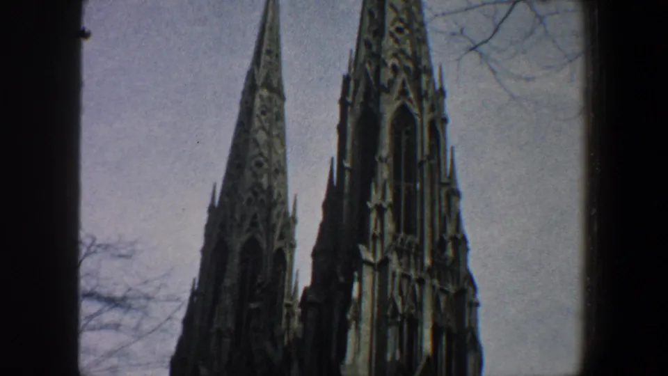 1960 New York City home-movie view of a Gothic-style church facade with two steep spires and ornate stone detailing.