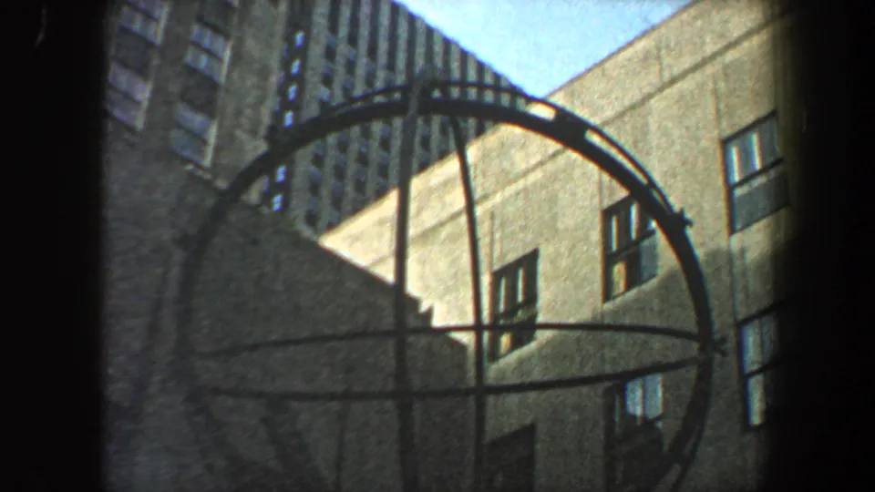 1960 New York City 8mm view of a circular metal structure set against high-rise building facades.