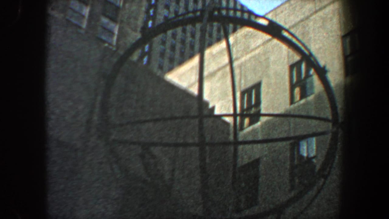 Circular metal sculpture framed against tall city buildings and sky.
