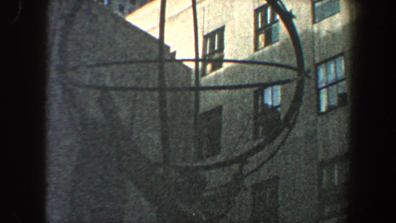 Circular metal structure shifted right, with building walls and windows behind it.