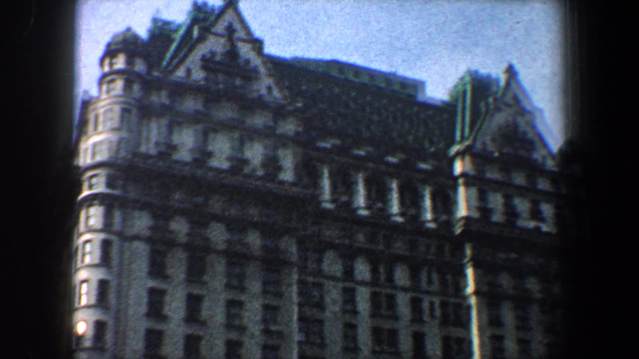 Tall ornate building facade with turrets, gables, rows of windows, and pale sky.