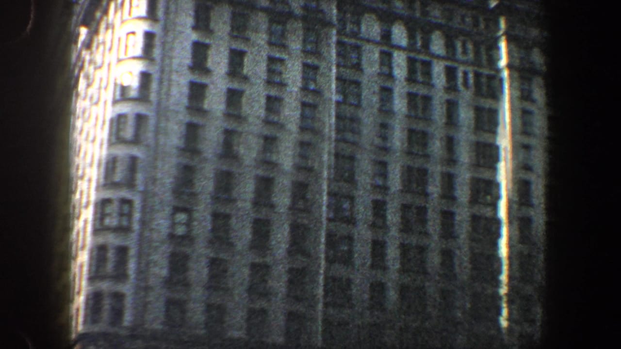 Tall high-rise facade with rows of windows and dark film-edge shadows.