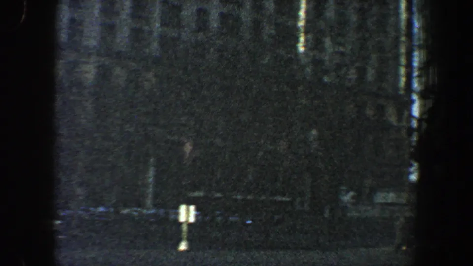 1960 New York City frame showing trees in front of a tall building's lower stories, with grain and dark edge shadows from the film scan.
