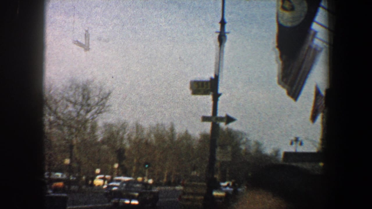 1960 New York City street view with flags, traffic, bare trees, and silhouetted architecture before the Chrysler Building view.