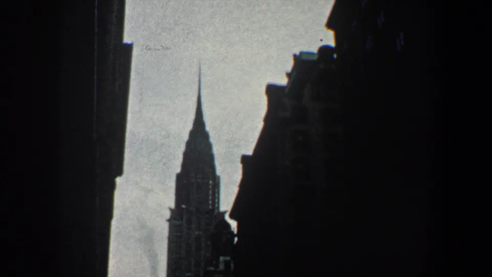 A visitor-shot 1960 New York view centers the Chrysler Building spire beneath dark foreground facades.