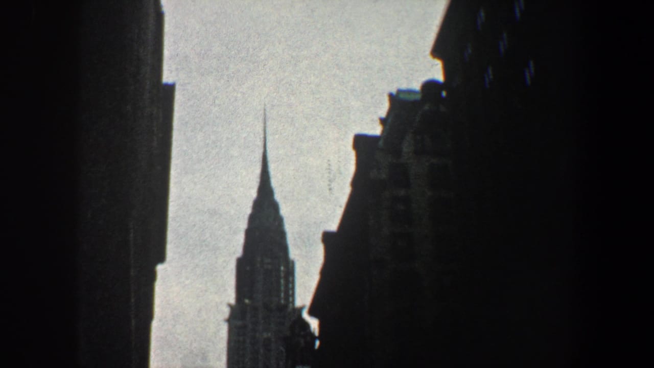 Chrysler Building spire framed between dark city buildings.