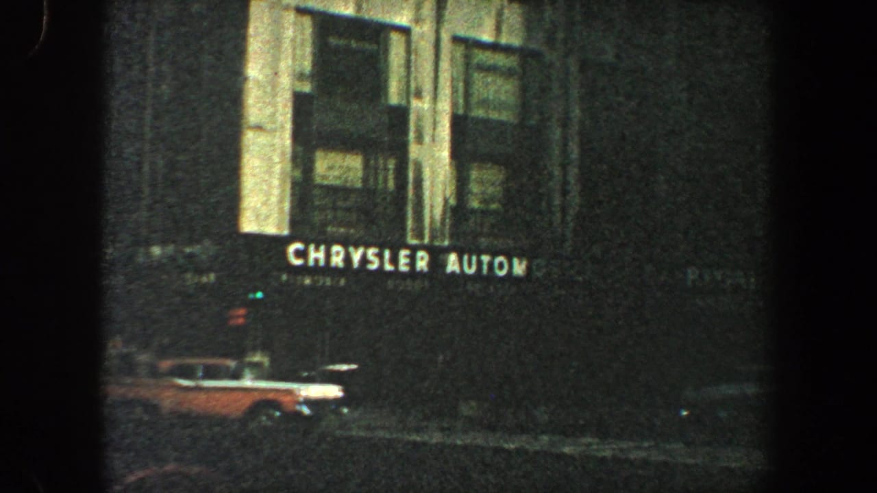 Chrysler Automobiles sign on a city building with a car at street level.