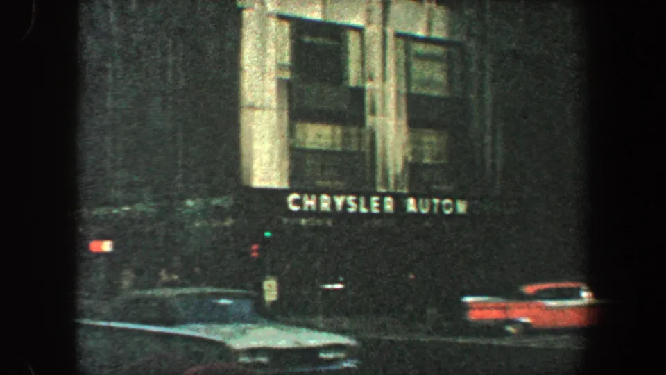 Street-level 1960 New York City footage showing Chrysler Automobiles signage, traffic, and mid-century cars.