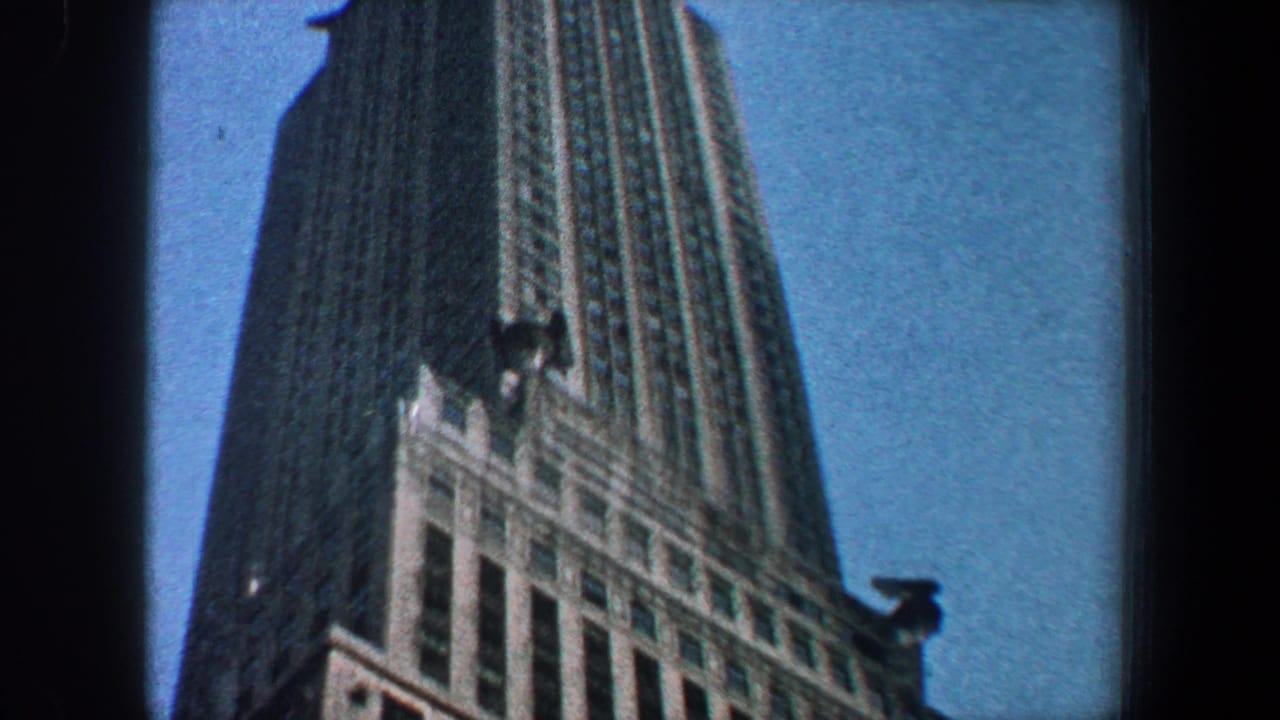 Low-angle view of the Empire State Building facade rising into blue sky.