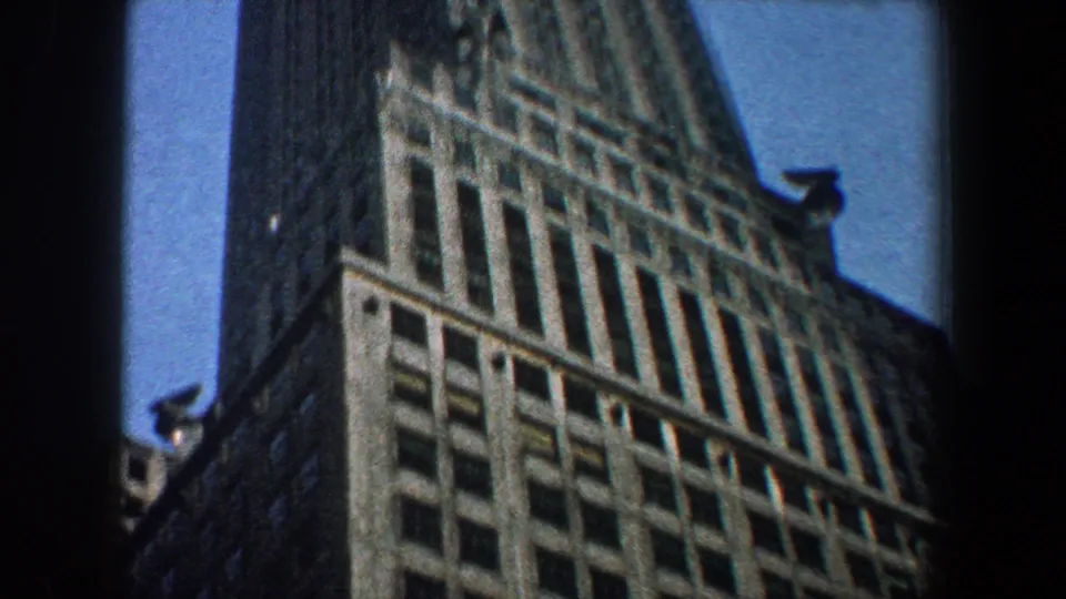 1960 New York City frame showing the Empire State Building facade, setbacks, and spire from a visitor-like low angle.