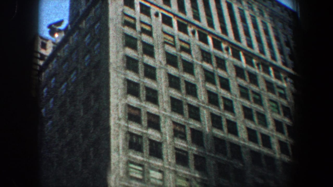 Low-angle view of a tall windowed building facade in soft 8mm color.