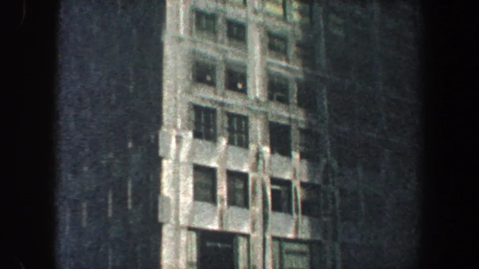 1960 New York City frame showing a closer section of the building facade, with vertical Art Deco-style details and dark windows.