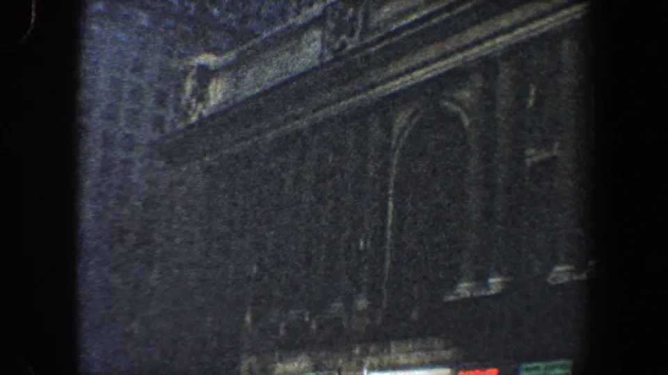 1960 New York City 8mm frame showing a dim historic facade with arched window forms, carved stonework, and visible film grain near the clip ending.