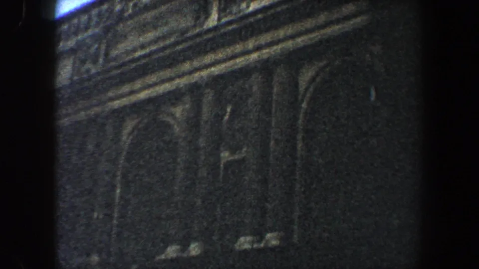 Dim 1960 New York City frame focused on upper facade stonework and an arched window area.