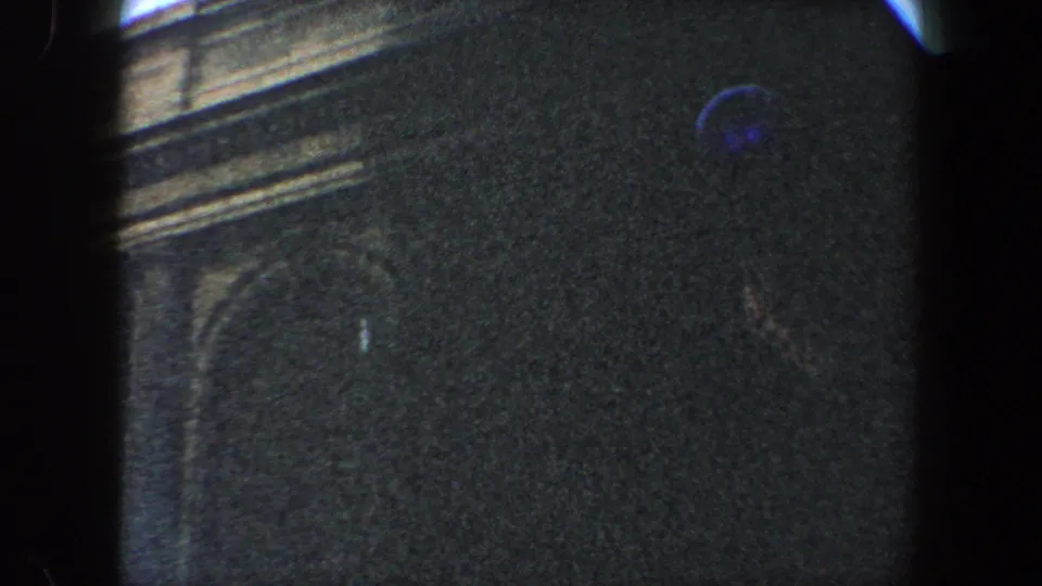 Late frame from the 1960 New York City clip showing a dark ornate facade and arched detail under low exposure.