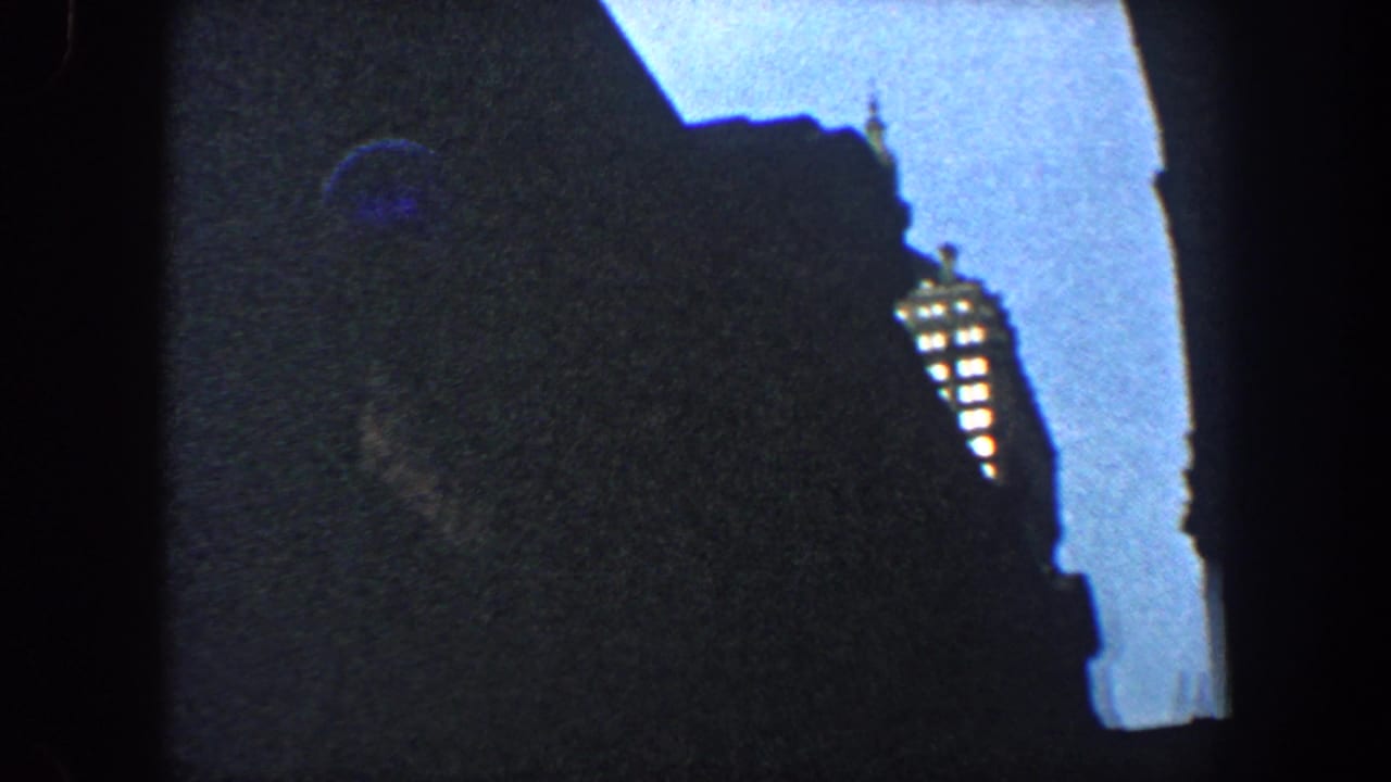 Shadowed building edge with a bright sky opening and a lit tower-like vertical detail.