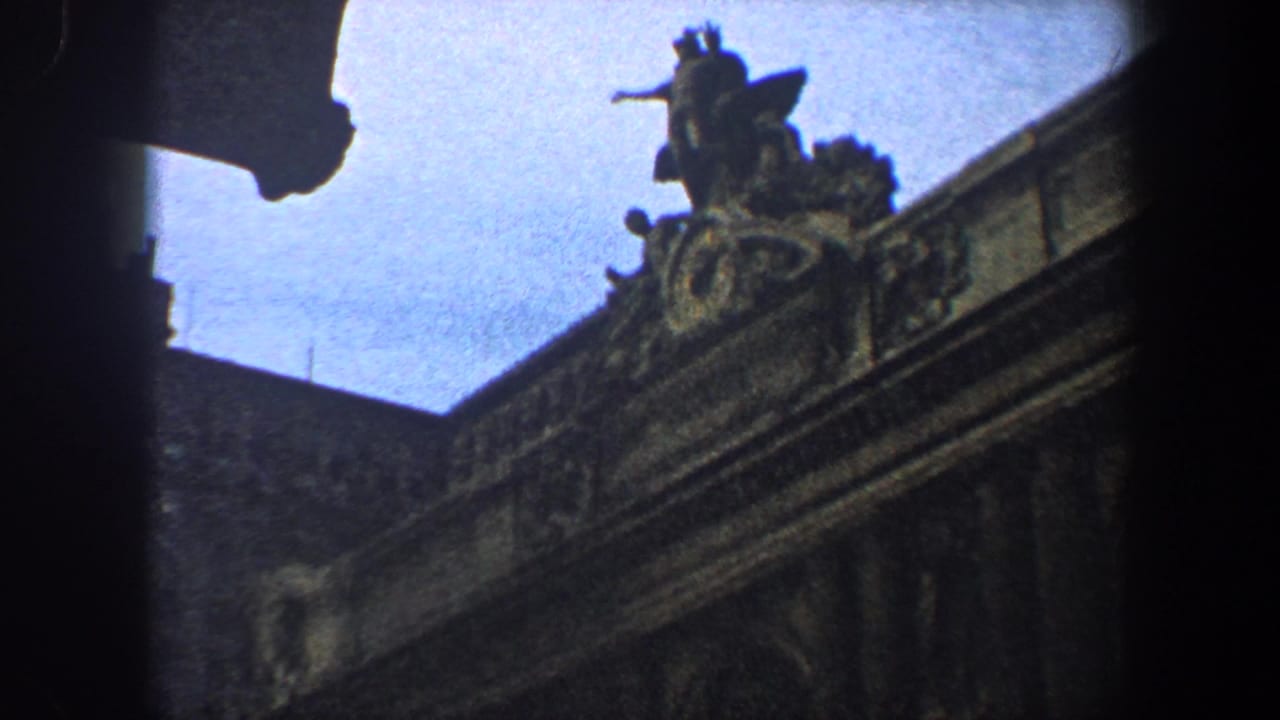 Upper corner of ornate stone building with roof sculpture and dark vignette.