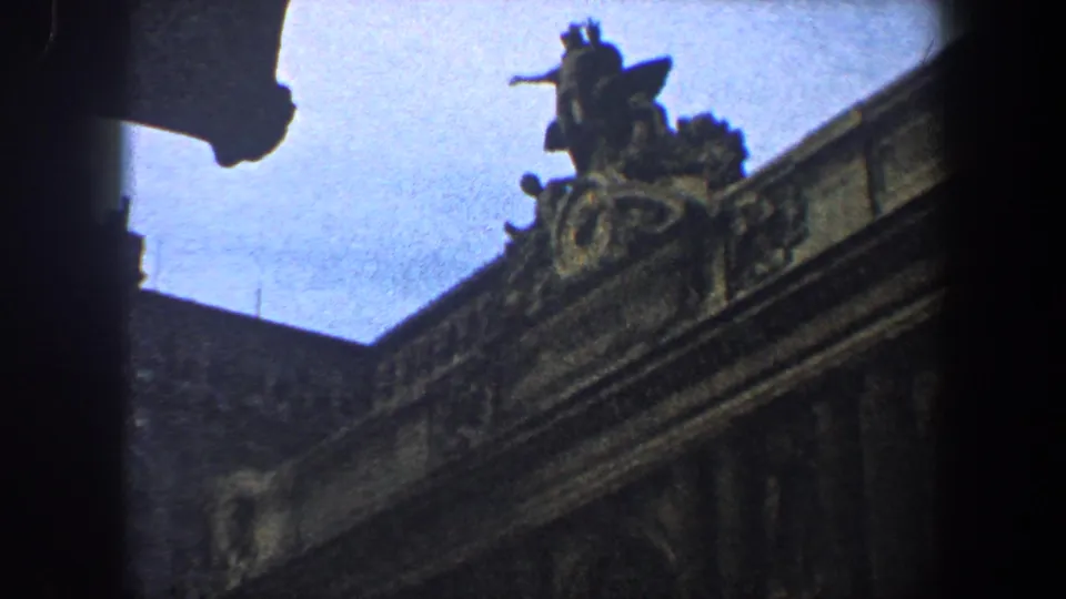 1960 New York City frame of a grand stone building corner, with roof sculpture, carved trim, and heavy dark edge vignetting.
