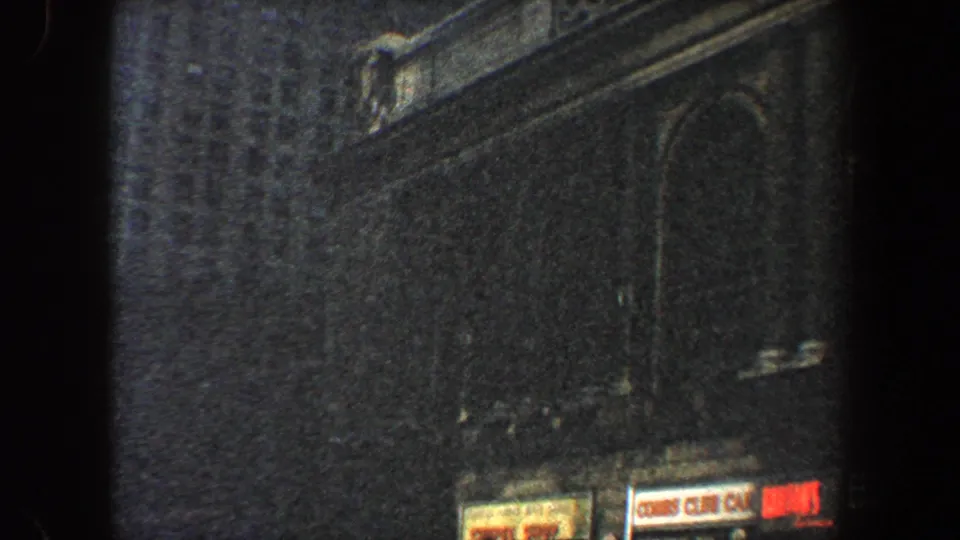 1960 New York City frame showing a dark historic facade with arched architectural detail and partial street-level signage at the bottom edge.