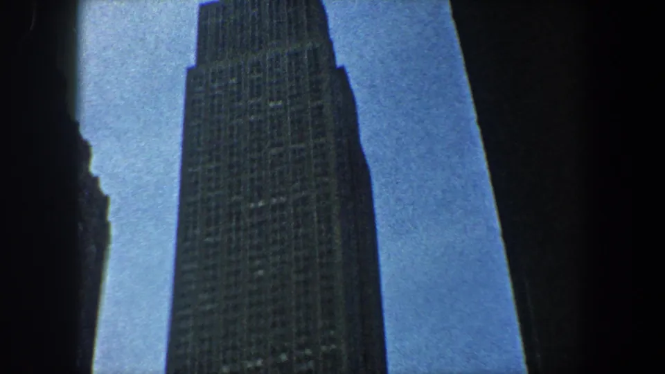1960 New York City 8mm frame with the Empire State Building extending upward beside a dark vertical foreground edge.