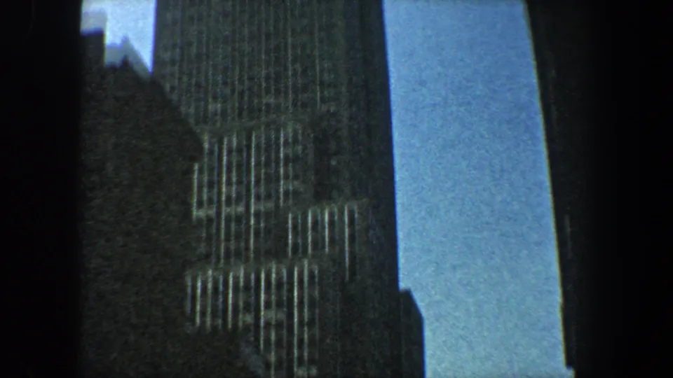 1960 New York City frame showing the Empire State Building with darker neighboring structures in the foreground.