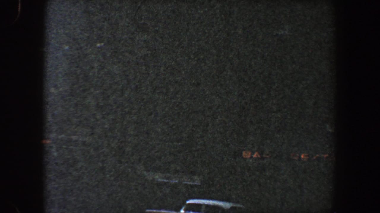 Dark building wall with faint windows and a partial vehicle roof near the lower edge.