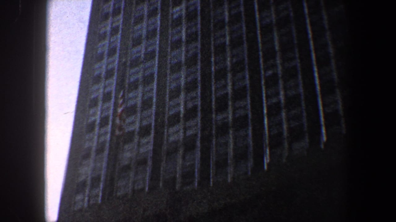 Low-angle view of a dark skyscraper facade rising against pale sky.