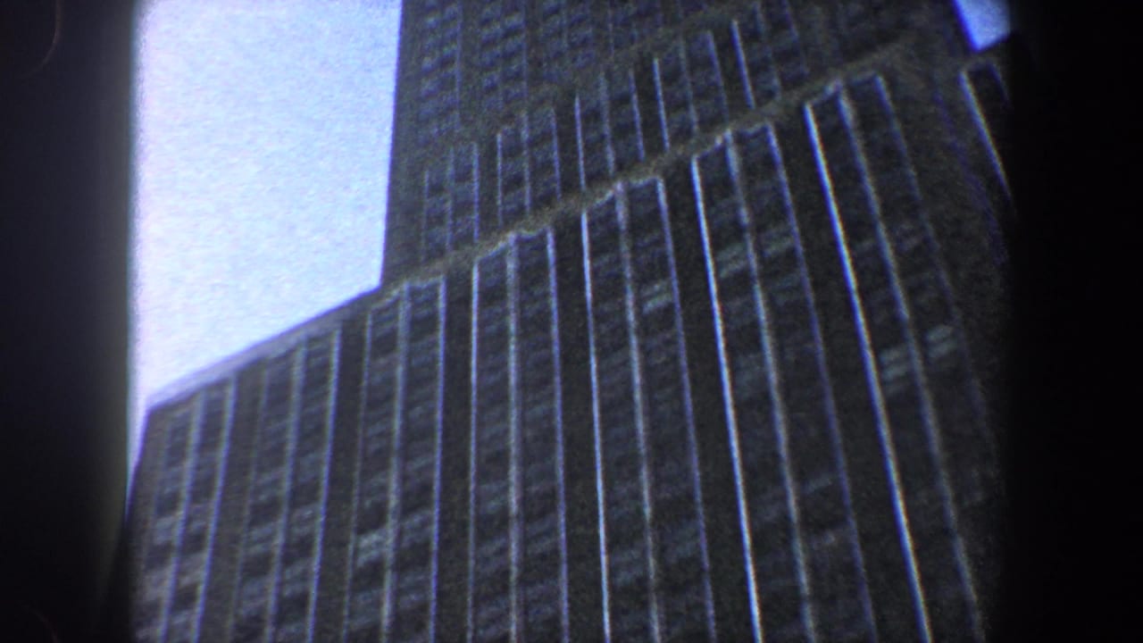 Tall building corner and window grid seen from below against blue sky.