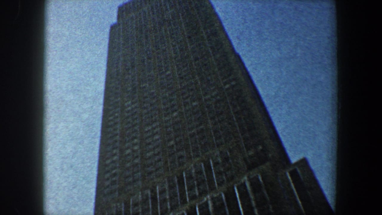 Low-angle view of the Empire State Building rising against a blue sky.