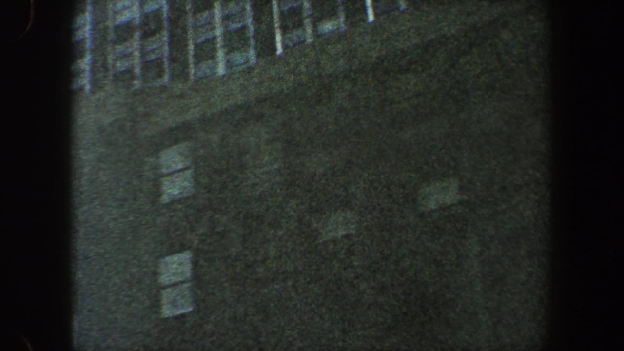 Shadowed building wall with rows of windows seen from a steep upward angle.
