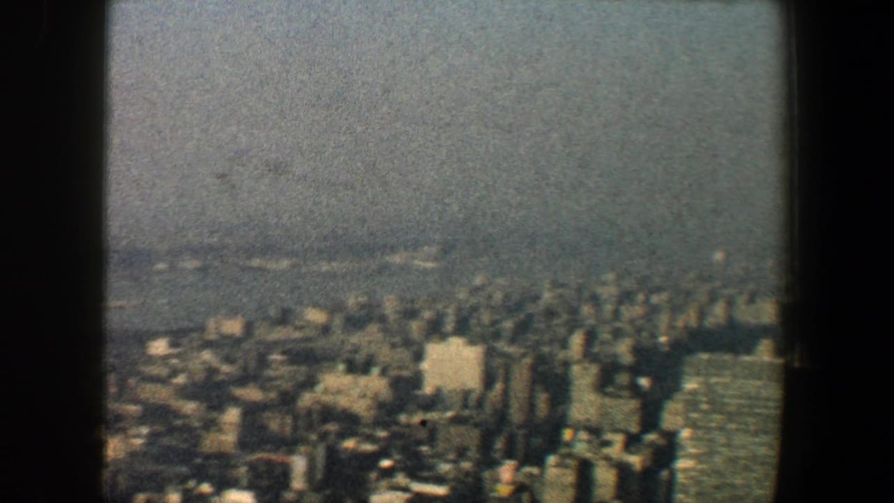 Soft high-angle view of dense skyscrapers beyond a dark vertical frame.