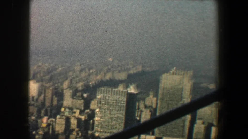 High-angle New York City overlook in 1960, with tall buildings below and dark diagonal framing across the view.