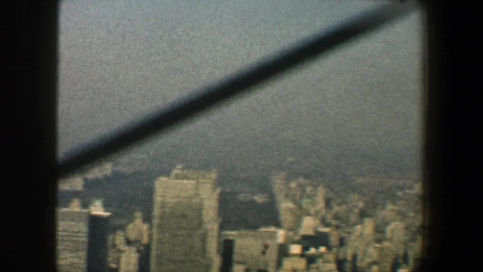 1960 New York City skyline from a high lookout, with diagonal supports crossing a soft, grainy city view.