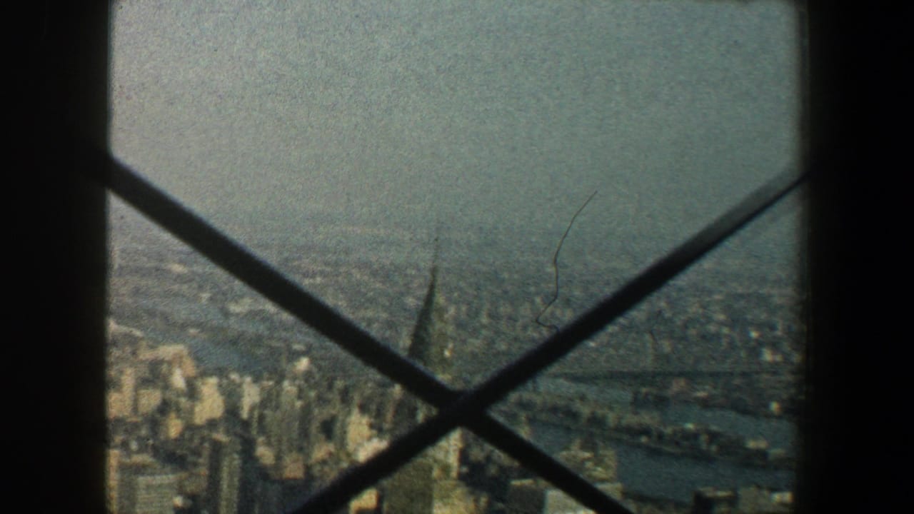 1960 New York City skyline viewed from the Empire State Building observation area through dark structural crossbars.