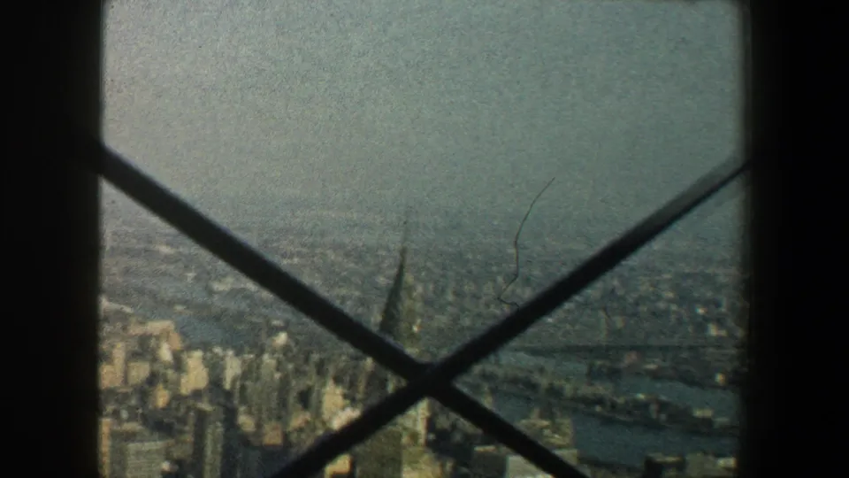 1960 New York City skyline viewed from the Empire State Building observation area through dark structural crossbars.