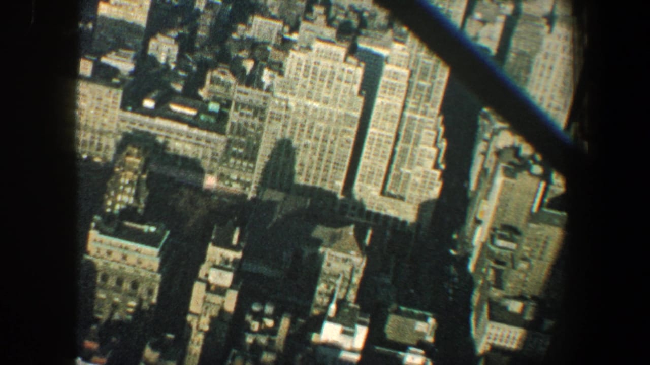 1960 New York City high-angle view of tightly packed buildings and streets partly obscured by dark observation-window framing.