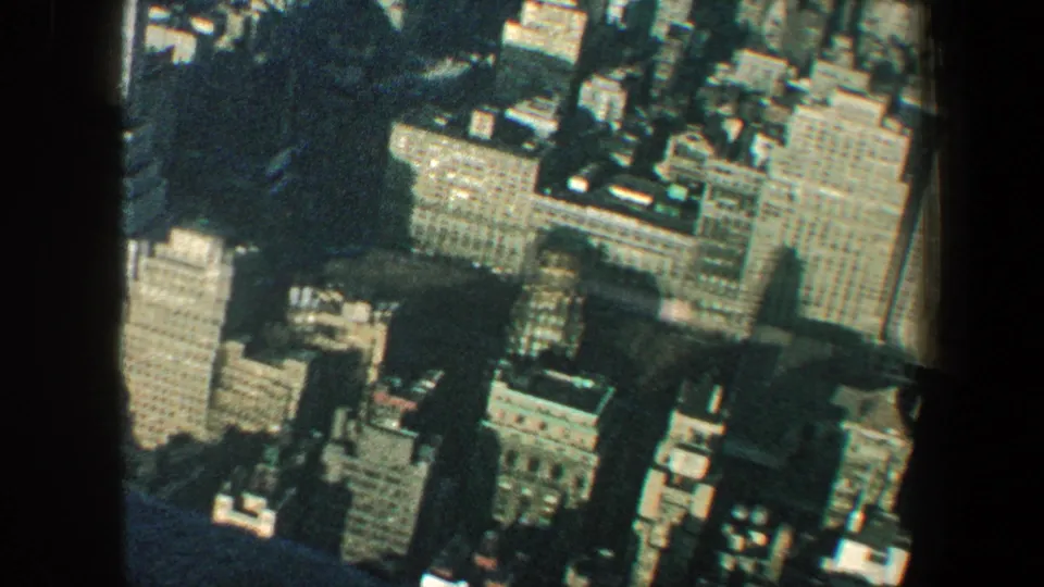 1960 New York City skyline detail from an elevated viewpoint, with office buildings and a dark foreground mullion visible.