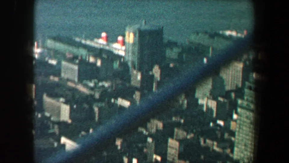 Elevated 1960 New York City view with Manhattan buildings, waterfront, and diagonal observation-deck fence bars.