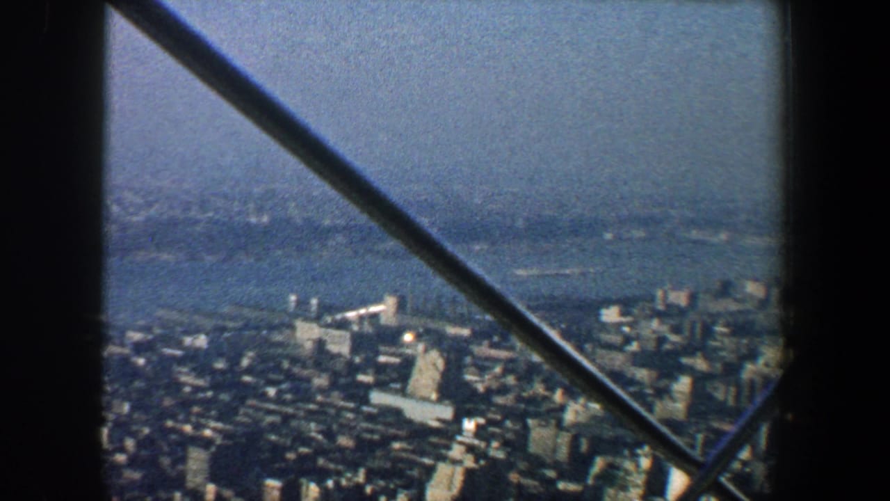 High city view with waterfront and distant haze framed by metal beams.