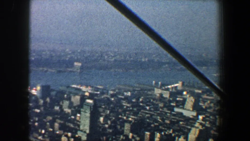 1960 New York City waterfront and clustered buildings seen from above, with soft focus and a dark diagonal beam.
