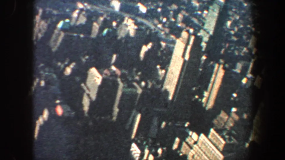 1960 New York City skyline view from above, with clustered high-rises and street grid softened by 8mm grain.