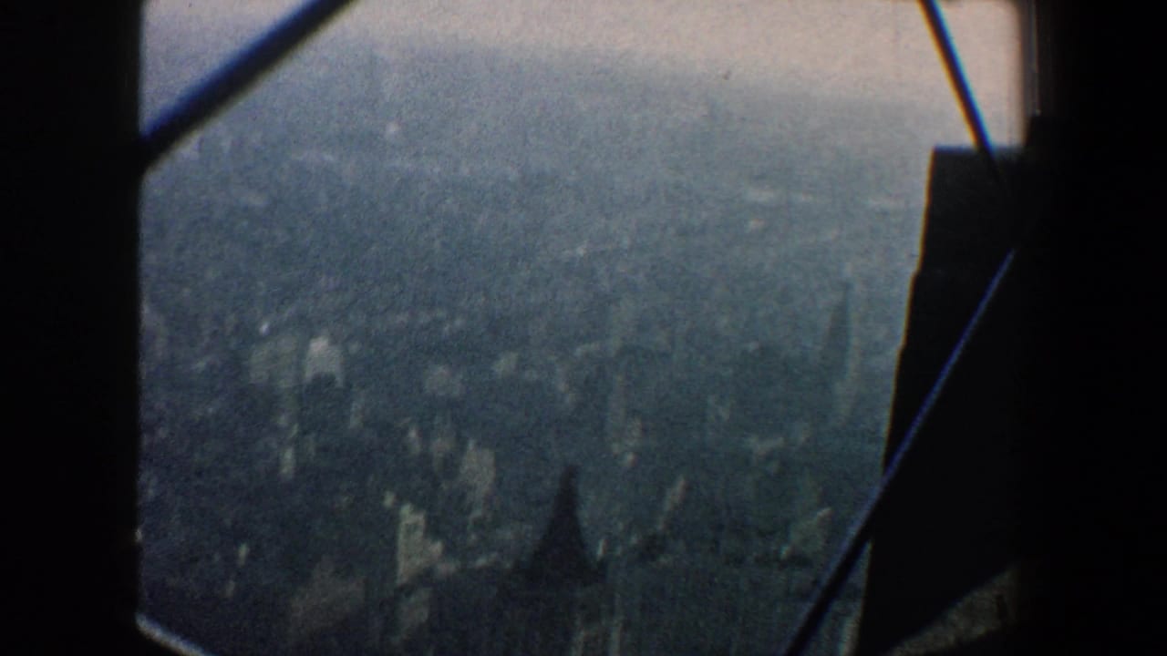 Hazy city view seen through dark window framing and diagonal beams.