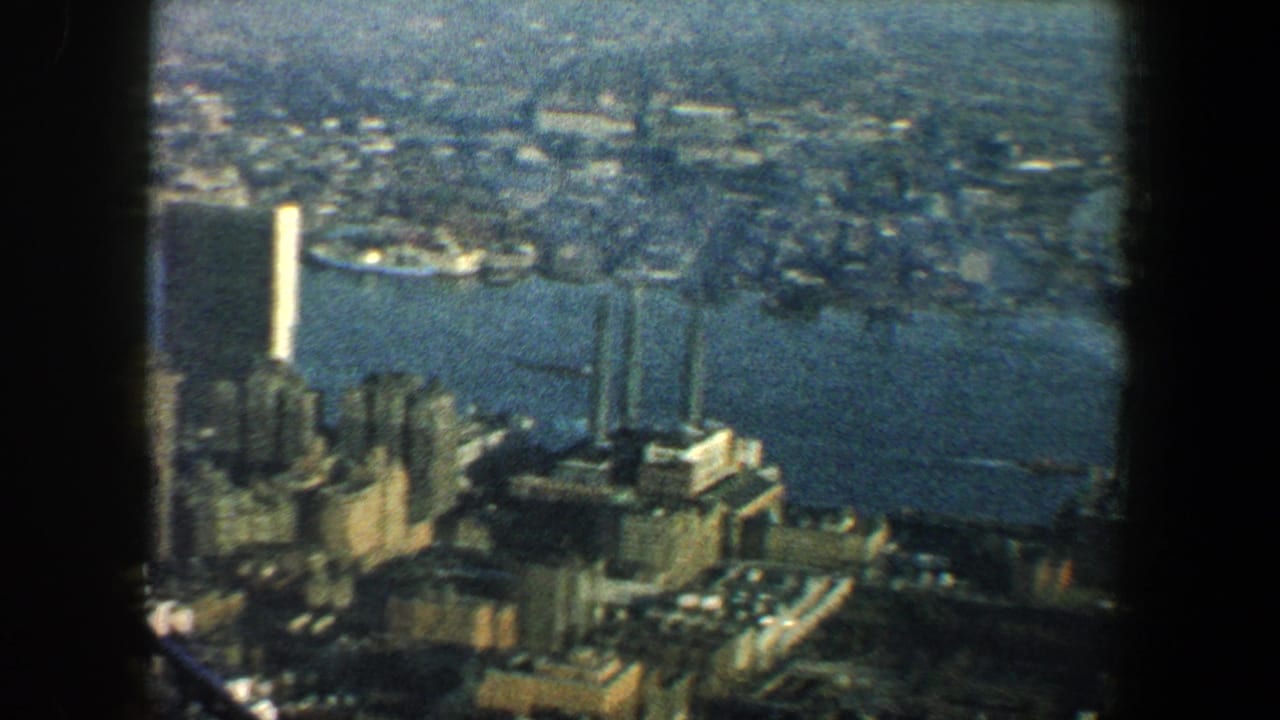 Aerial view of waterfront towers, river water, piers, and distant city blocks.
